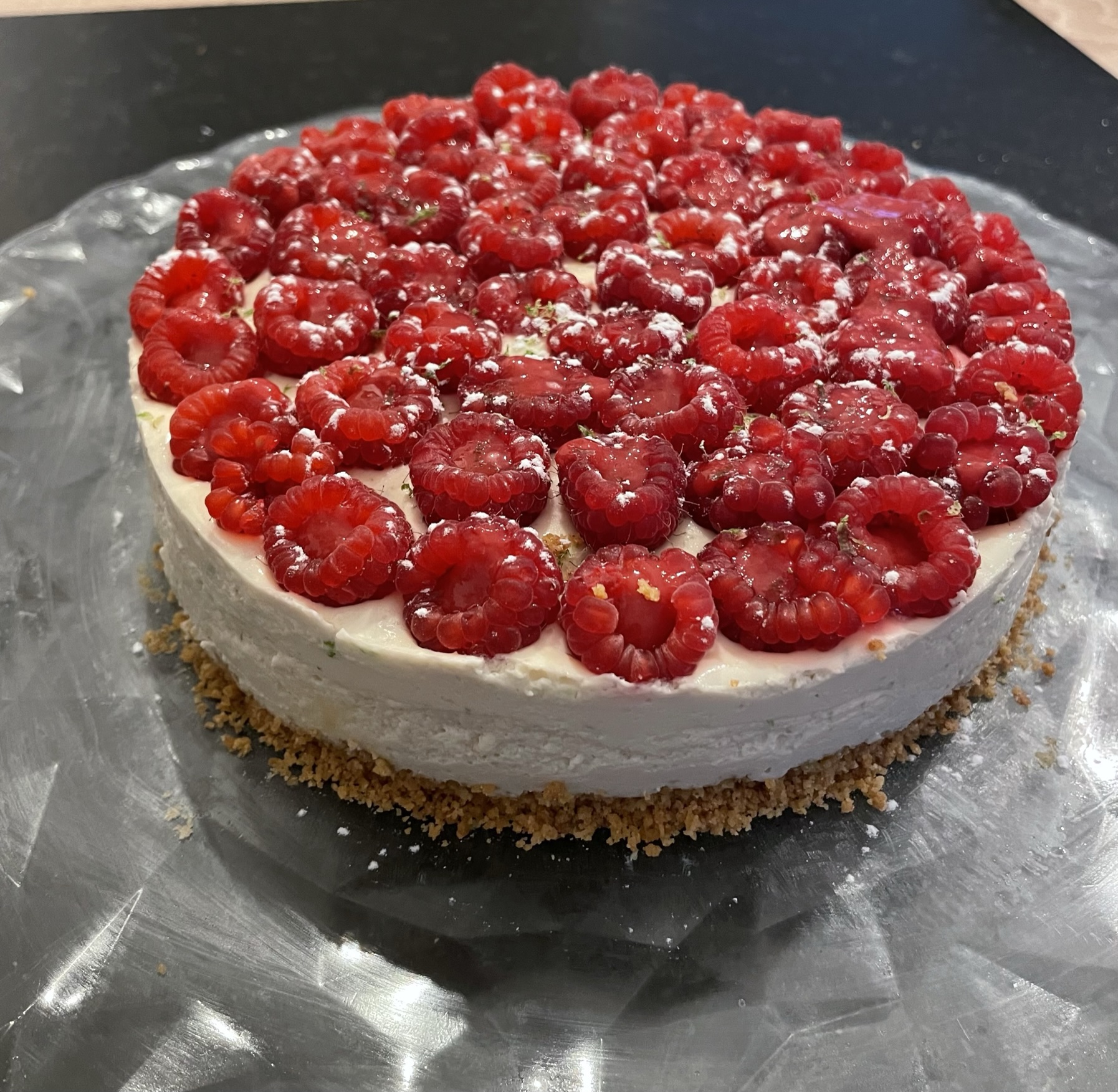 Cheesecake à la mousse onctueuse, recouvert de framboises fraîches, sur une base de biscuit émietté.