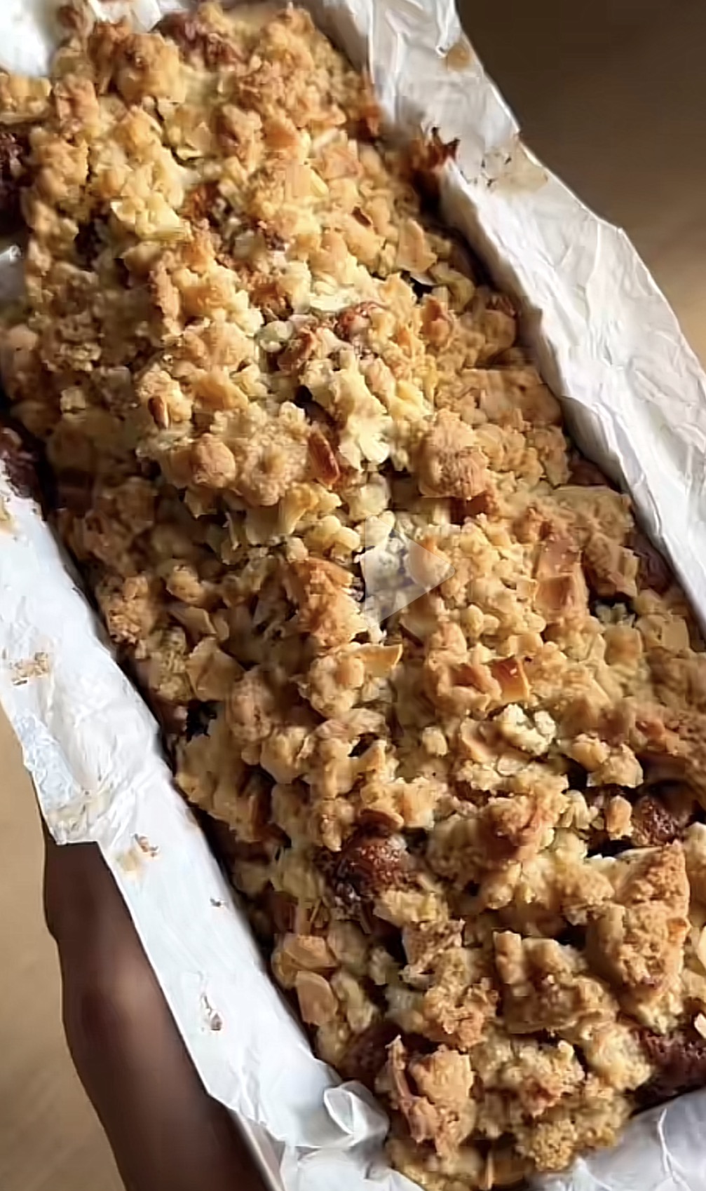 Cake aux pommes caramélisées recouvert d'un crumble doré, posé sur une planche.